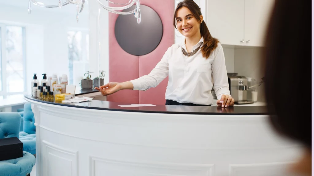 Администратор салона краосты привествует клиентку за стойкой
